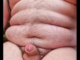 A chubby gay man masturbates outside.